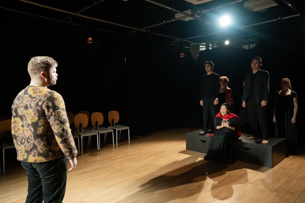 Actor stands facing a group of actors on stage during the final presentation of The Winter's Tale.